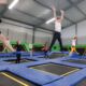 Grupa dzieci skacze wysoko ponad trampolinami.