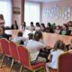 Przy złączonych kilku stołach w świetlicy wiejskiej siedzi na czerwonych krzesłąch kilkanaście młodych i starszych osób. Słuchają dyrektorki Gminnego Ośrodka Kultury i koordynatorki projektu.