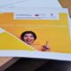 Na zdjęciu widać grafikę - logo projektu w żółtych barwach. Na grafice widać młodą, uśmiechniętą kobietę z podniesionym w górę wskazującym palcem. Palec wskazuje na napis "Cześć, jesteśmy Twoim Domem Kultury!"