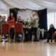 Grupa uczestników spaceru zielarskiego rozmawia przy stole smakując potrawy, przysmaki zrobione z ziół nazbieranych podczas spaceru. Instruktorka GOK opowiada o ziołach i dzieli się rzepisami.